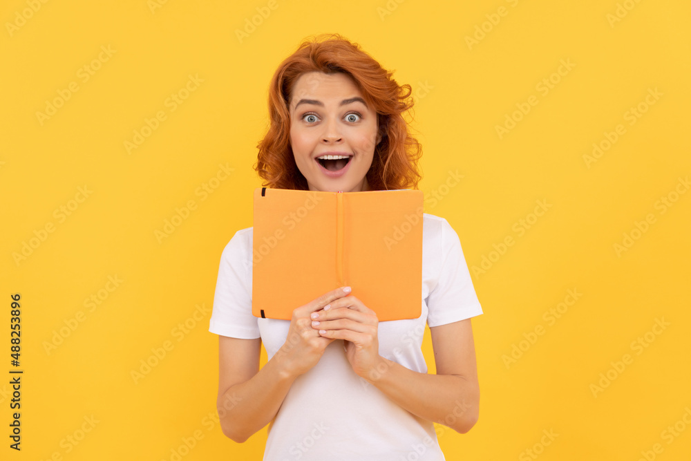 amazed girl hold copybook on yellow background, school