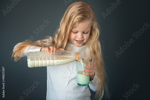 Little girl pours milk into a glass