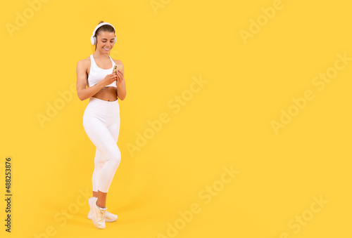 Fototapeta Naklejka Na Ścianę i Meble -  sport woman with headphones and smartphone on yellow background. copy space