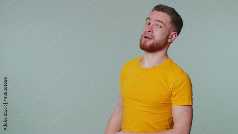 Smiling playful happy man in yellow t-shirt blinking eye, looking at camera with toothy smile winking and flirting, expressing optimism. Young handsome adult guy alone isolated on gray wall background Smiling playful happy man in yellow t-shirt blinking eye, looking at camera with toothy smile winking and flirting, expressing optimism. Young handsome adult guy alone isolated on gray wall background