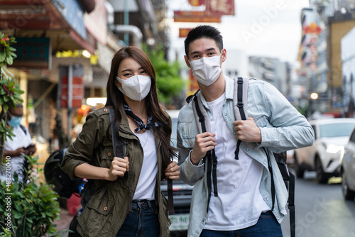 Portrait of Asian couple wear mask, travel in city for honeymoon trip. 