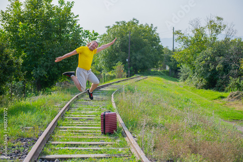 Fototapeta Naklejka Na Ścianę i Meble -  funny newcomer with a suitcase jumping on the railroad