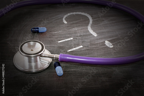 medicine, concept, stethoscope and pills on a black board, chalk a question mark