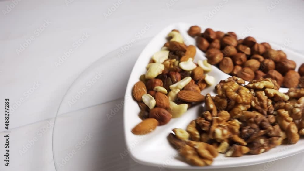 Various nuts close-up on a rotating white plate on a white wooden table. 4k raw video. Various nuts close-up on a rotating white plate on a white wooden table. 4k raw video.