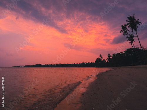 Scenic view of peaceful tropical island beach with iconic tall coconut palm tree against sunset cloudy twilight sky. Koh Mak Island, Trat, Thailand.