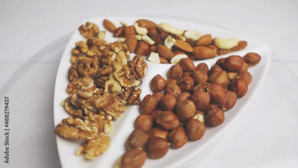 Various nuts close-up on a rotating white plate on a white wooden table. 4k raw video. Various nuts close-up on a rotating white plate on a white wooden table. 4k raw video.