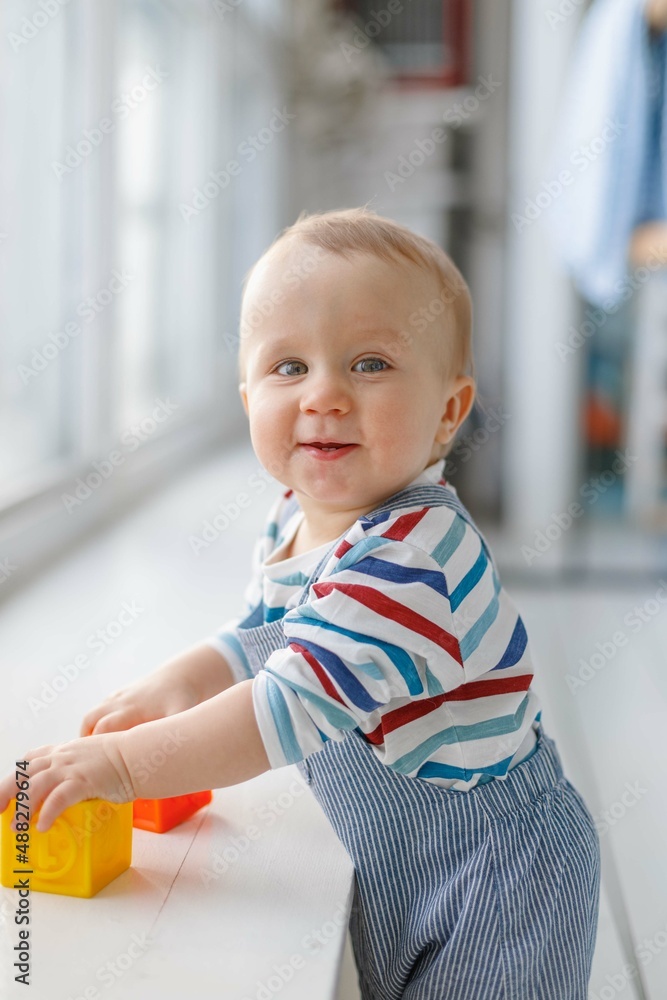 One-year-old baby plays with cubes in the apartment white background One-year-old baby plays with cubes in the apartment white background