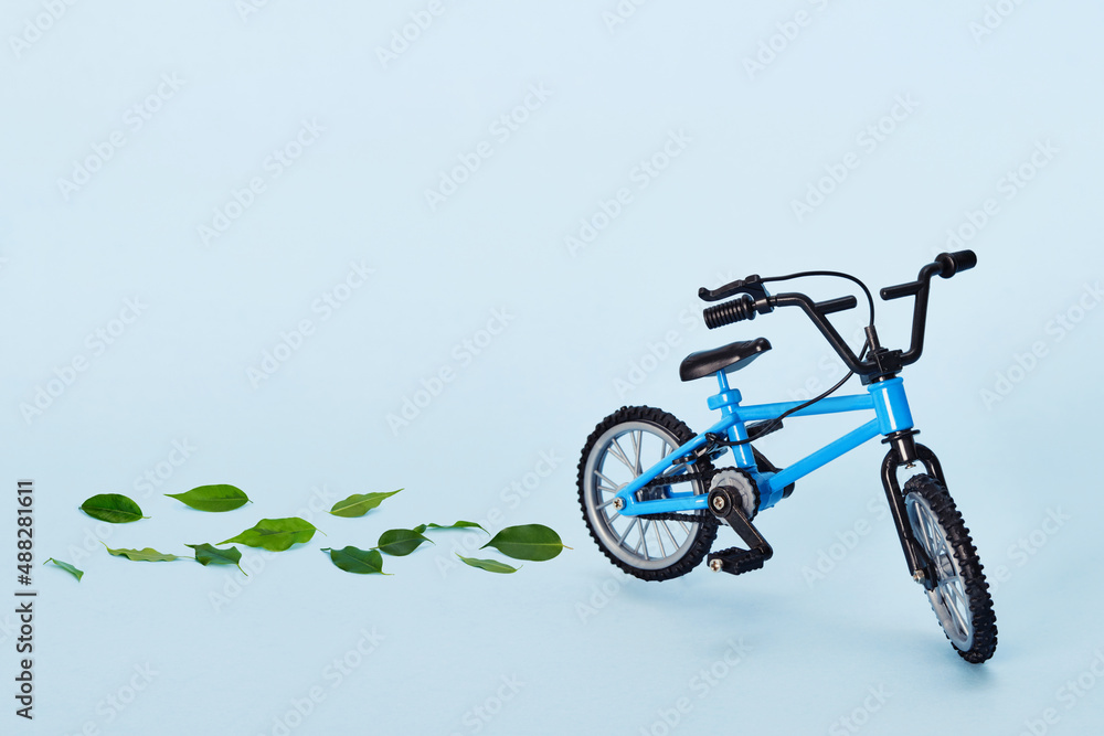 World bicycle day. Bicycle emitting fresh green leaves on blue background. Sustainable and healthy concept