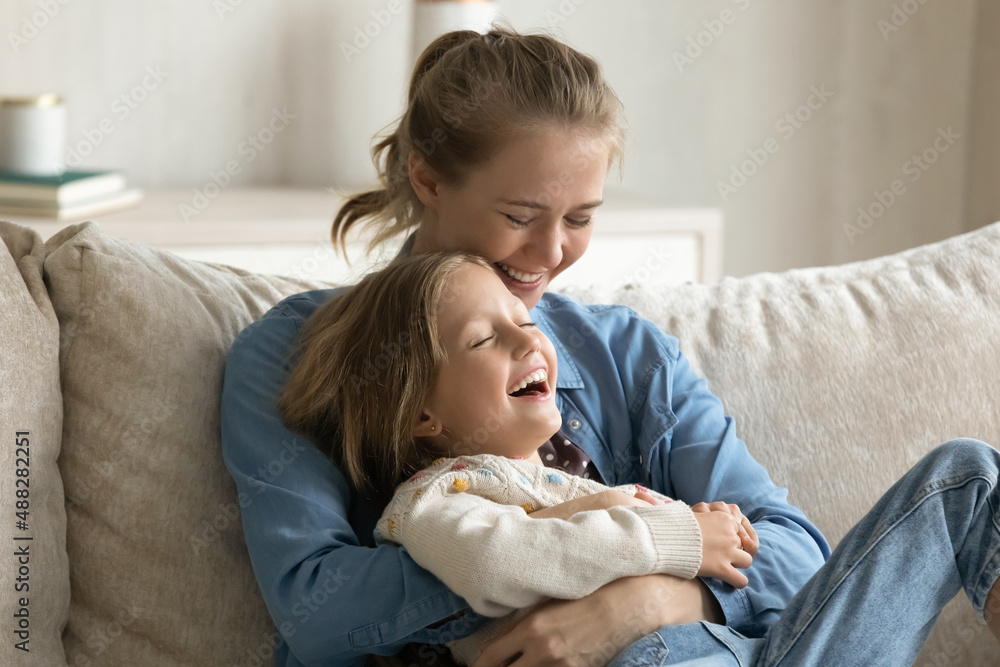 Happy loving young mother laughing and tickling joyful daughter girl, hugging, holding child in arms, enjoying family leisure time at home, having fun. Mom and kid affectionate, motherhood concept Happy loving young mother laughing and tickling joyful daughter girl, hugging, holding child in arms, enjoying family leisure time at home, having fun. Mom and kid affectionate, motherhood concept