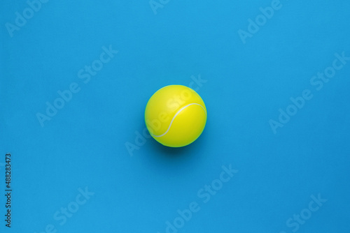 Minimal concept of a large tennis ball on a blue background. Flat lay.