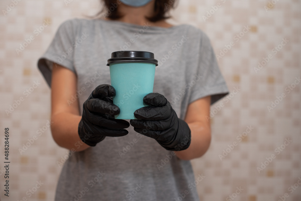 Naklejka premium A woman in gloves holds a turquoise craft glass