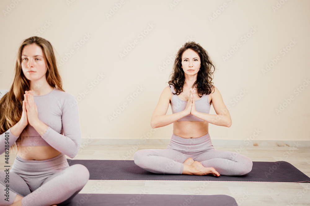 Well looking middle aged sporty woman, fitness instructor in pink sportswear doing stretching and pilates on yoga mat in the studio with mirror. Female fitness yoga. Healthy lifestyle and harmony. Well looking middle aged sporty woman, fitness instructor in pink sportswear doing stretching and pilates on yoga mat in the studio with mirror. Female fitness yoga. Healthy lifestyle and harmony.