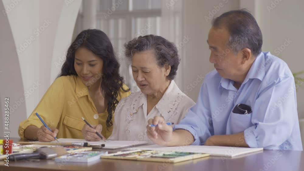 Young beautiful woman drawing pictures with senior people. She teaching her student to drawing picture at her class. Young beautiful woman drawing pictures with senior people. She teaching her student to drawing picture at her class.