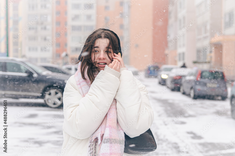 Portrait of a teenage girl outdoors with a smartphone in snowy winter weather.