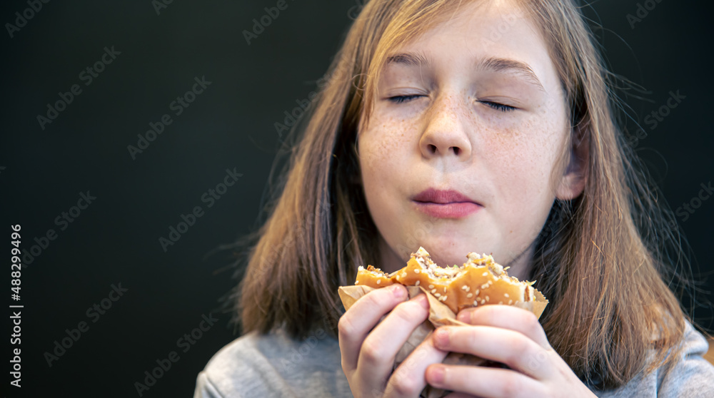 A little girl with freckles eats a burger. A little girl with freckles eats a burger.