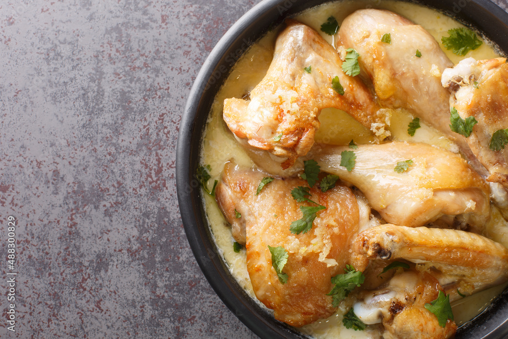 Shkmeruli is a traditional Caucasian Georgian dish of chicken in garlic sauce closeup in the pot on the table. Horizontal top view from above Shkmeruli is a traditional Caucasian Georgian dish of chicken in garlic sauce closeup in the pot on the table. Horizontal top view from above