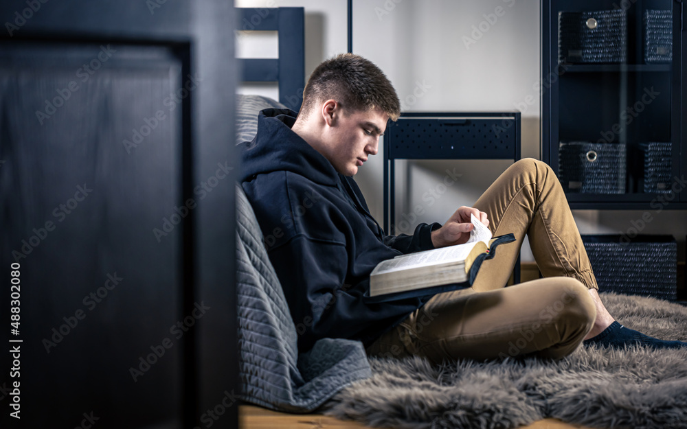 A young man sits in a room and reads the Bible. A young man sits in a room and reads the Bible.