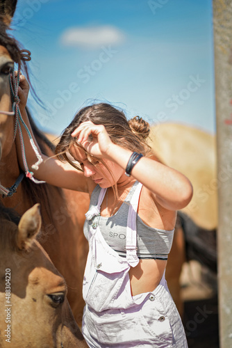 A young beautiful girl works on a horse farm.