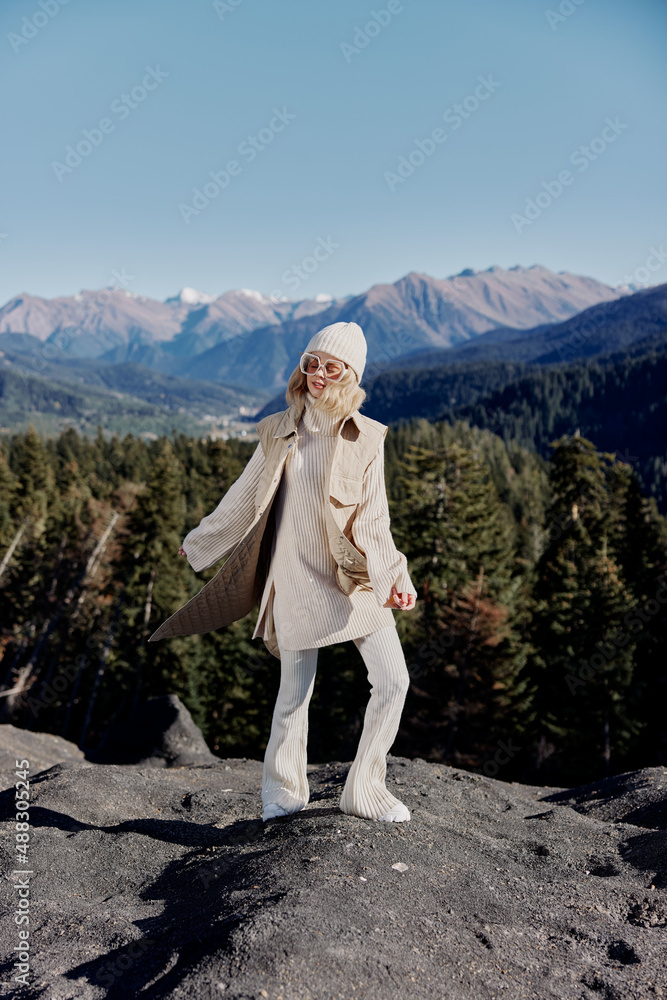 young woman in autumn clothes stands on a rock blue sky relaxation young woman in autumn clothes stands on a rock blue sky relaxation
