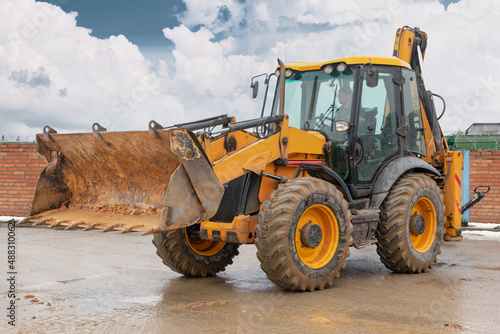 The excavator backfills the pit with the front bucket. Moves soil around the construction site. Close-up. Heavy construction equipment.