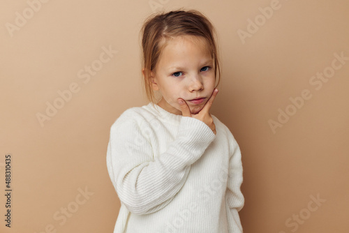 Portrait of happy smiling child girl in white sweater posing hand gestures isolated background