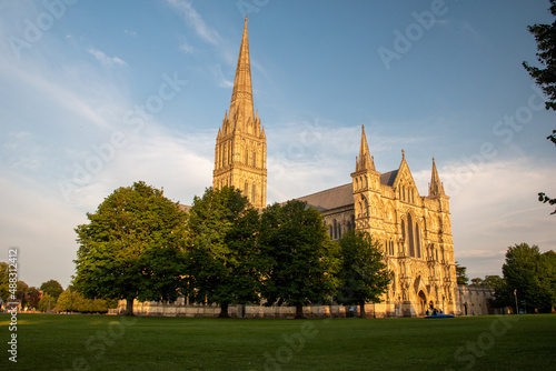 The spire of Salisbury Cathedral, Wiltshire, against a clear blue sky at golden hour. July 2021