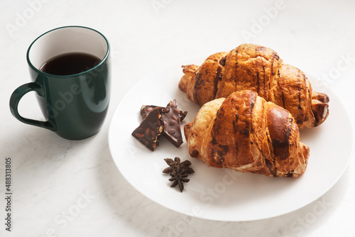 delicious  crispy croissants  chocolate  hot coffee in the blue cup and kitchen towel on plate on marble table