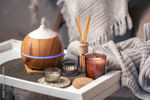 A cozy composition with an aroma diffuser and candles in a home interior. photo