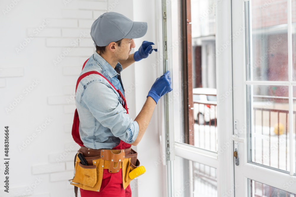 handsome young man installing bay window in a new house construction site. handsome young man installing bay window in a new house construction site.