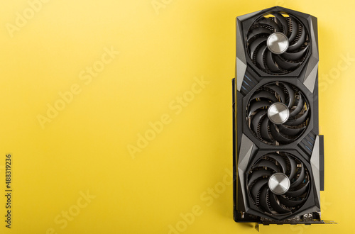 Game video card, video card adapter on a yellow background for video games and cryptocurrency mining. Computer parts. GPU card. copy space. photo
