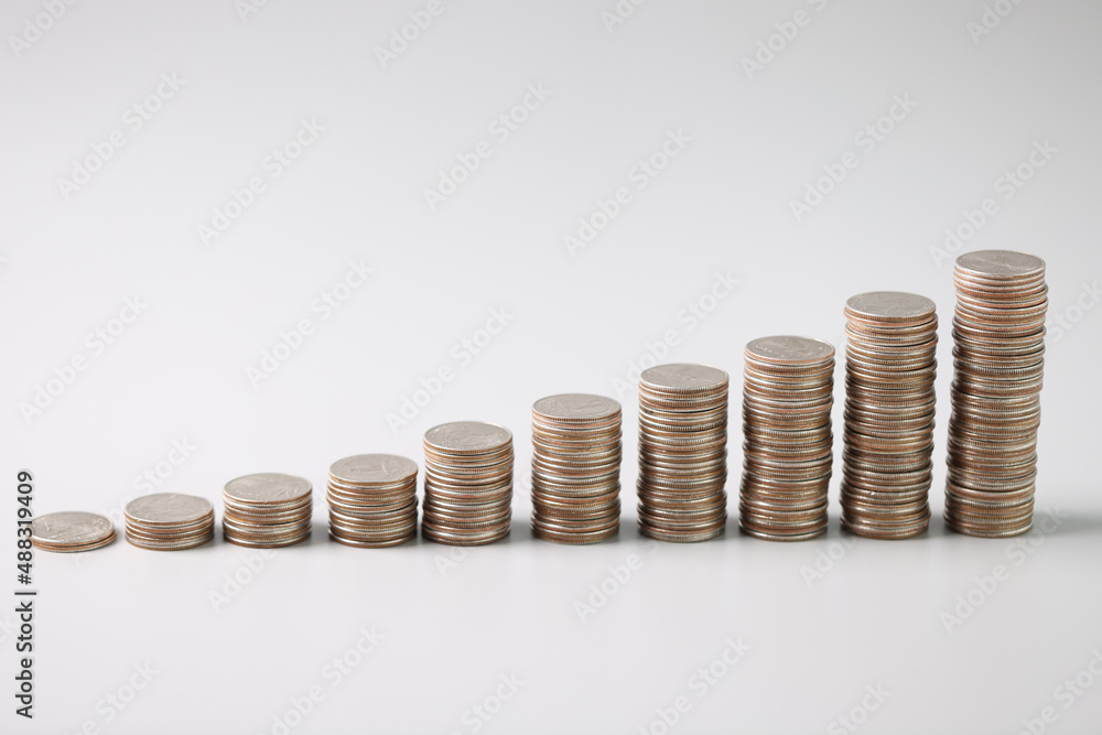 Stacks of silver coins in ascending order on light gray background Stacks of silver coins in ascending order on light gray background