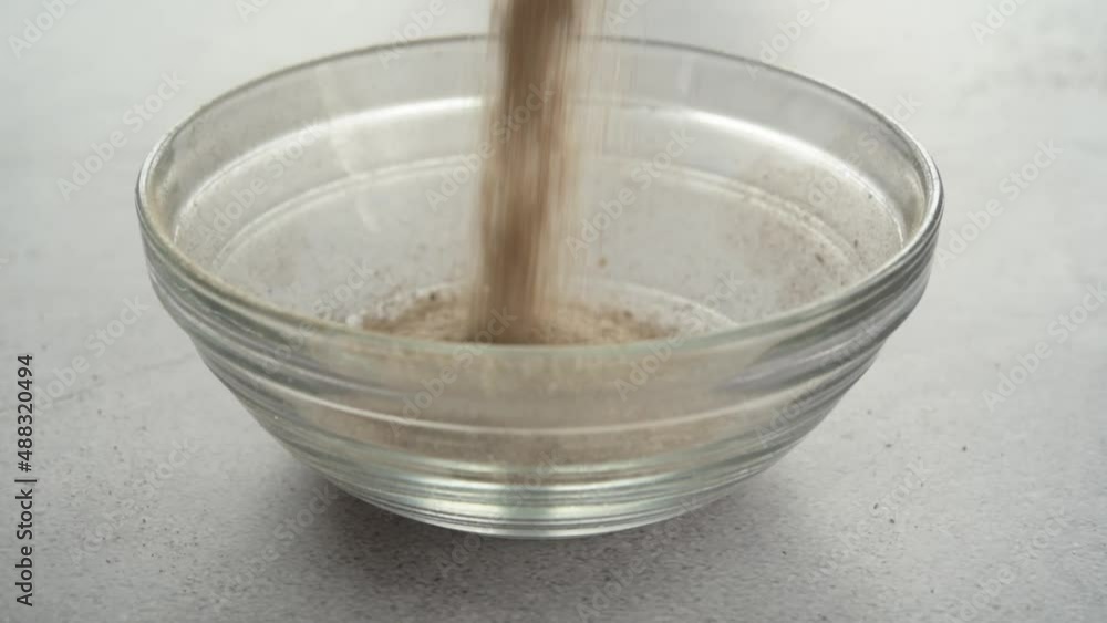 Filling a glass bowl with psyllium husk dietary fiber supplement Filling a glass bowl with psyllium husk dietary fiber supplement