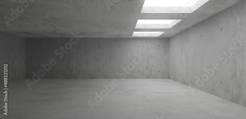 Empty modern abstract concrete room with light thru rectangular ceiling openings on the right and rough floor - industrial interior background template