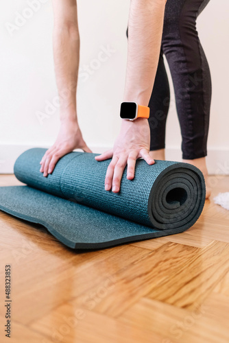 Close up of a woman's hands is rolling up exercise mat and preparing to doing yoga. Fitness concept.