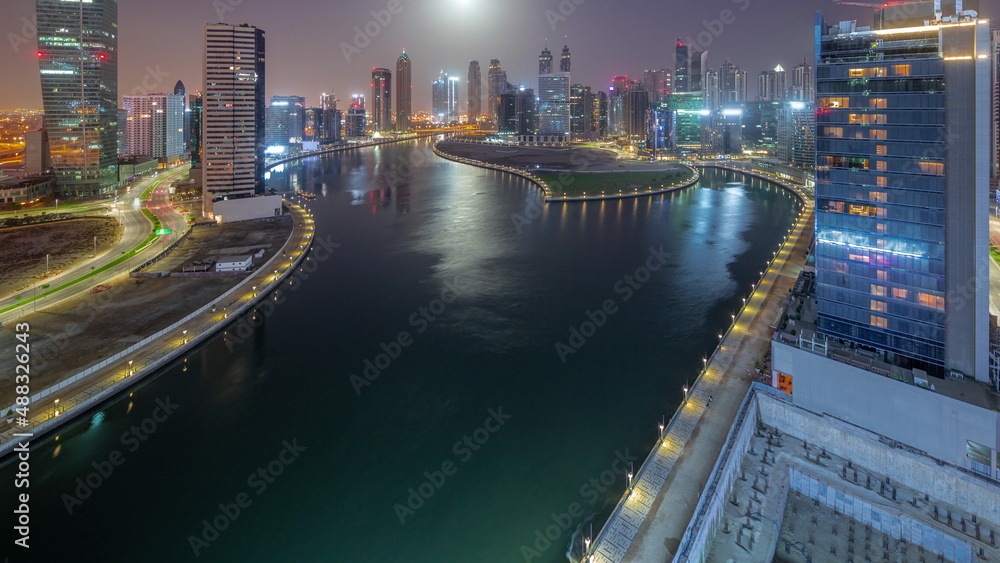 Fototapeta premium Cityscape of skyscrapers in Dubai Business Bay with water canal aerial night to day timelapse