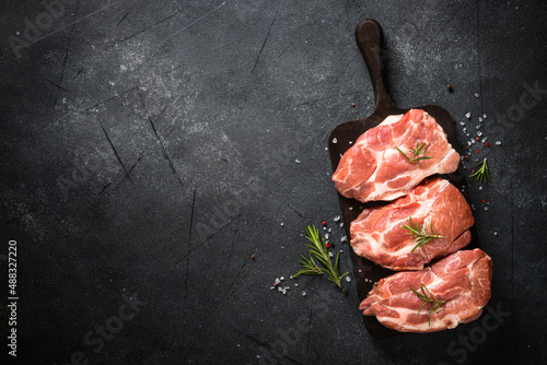 Raw meat. Fresh meat steaks with herbs and spices at black background. Top view with space for design.