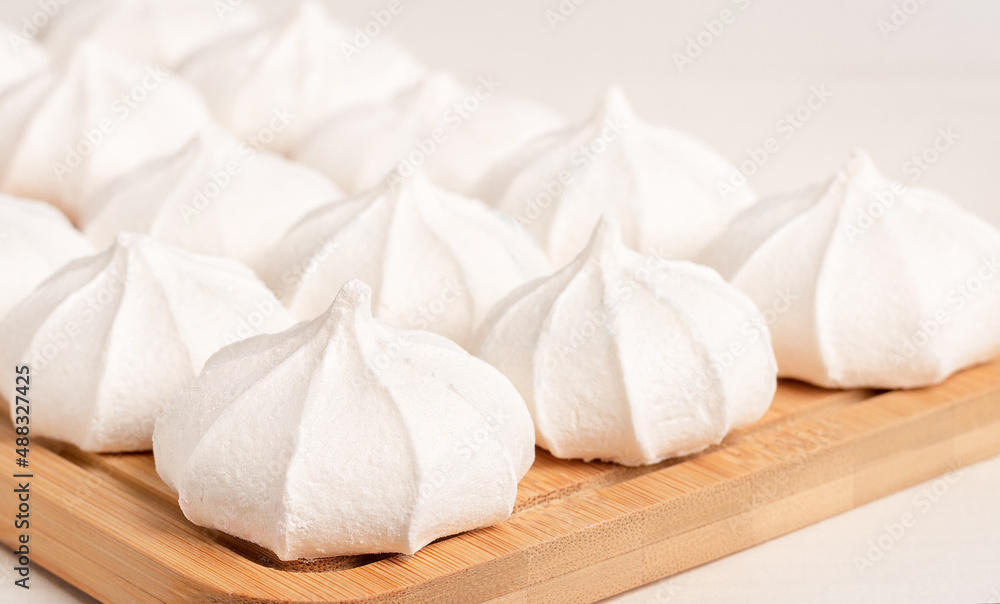 Light white meringues on a wooden board. Light white meringues on a wooden board.