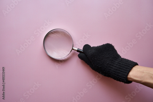 lupa i czarna rękawiczka na różowym tle