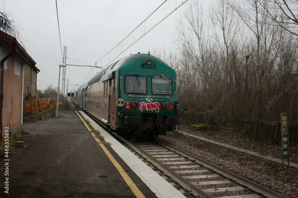 Naklejka premium passage of a local train in a small country station in Italy having a bad day