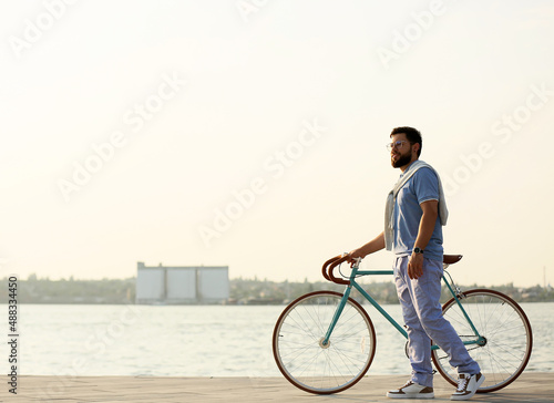 Young bearded man with bicycle near river © Pixel-Shot