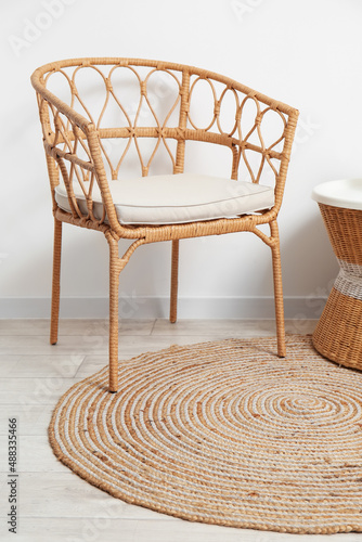 Comfortable wicker chair and stylish rug in room photo
