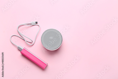 Power bank with USB cable and speaker on pink background