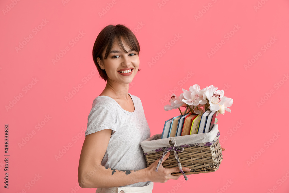 Beautiful young woman with many books and flowers on pink background Beautiful young woman with many books and flowers on pink background