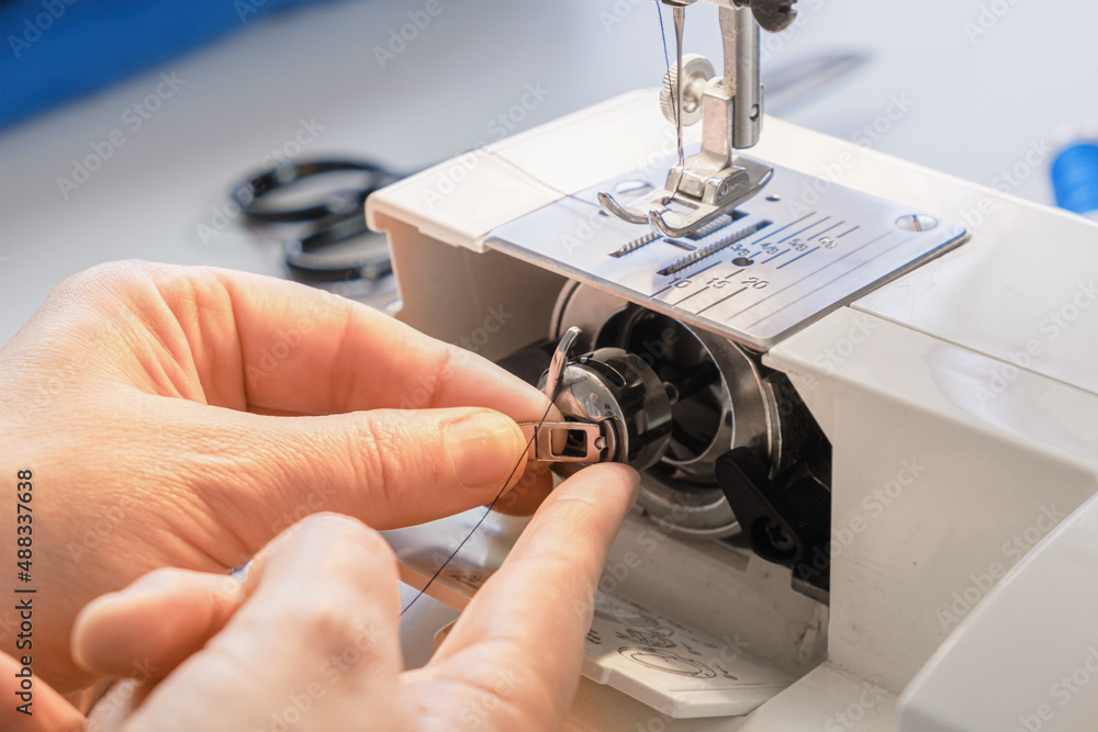 Seamstress pulling bobbin of an electric sewing machine Stock Photo Adobe Stock