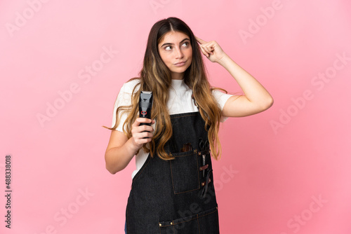 Young hairdresser woman isolated on pink background having doubts and thinking