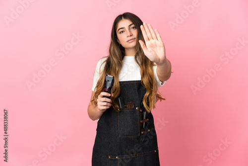 Young hairdresser woman isolated on pink background making stop gesture