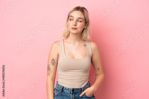 Young caucasian woman isolated on pink background having doubts while looking side © luismolinero