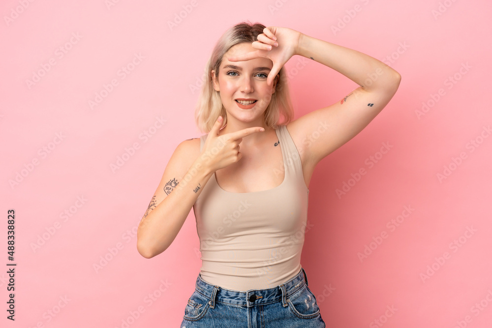 Young caucasian woman isolated on pink background focusing face. Framing symbol Young caucasian woman isolated on pink background focusing face. Framing symbol