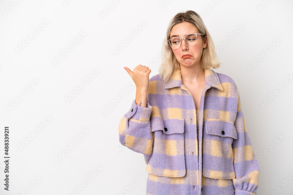 Young caucasian woman isolated on white background unhappy and pointing to the side Young caucasian woman isolated on white background unhappy and pointing to the side