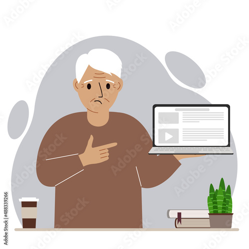 Sad grandfather holding a laptop computer with one hand and pointing at it with the other. Laptop computer technology concept.